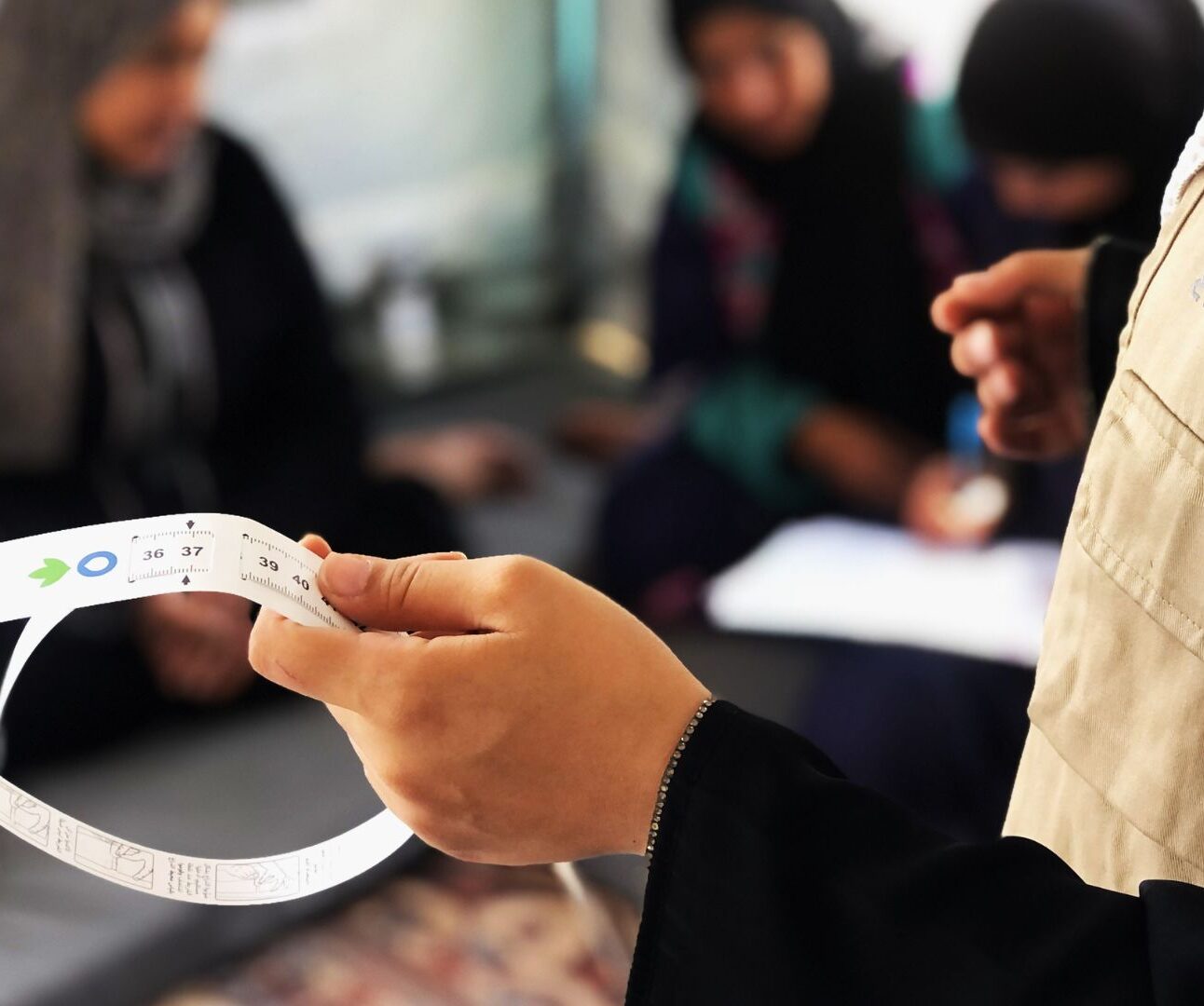 Action Against Hunger team member holding MUAC malnutrition band.