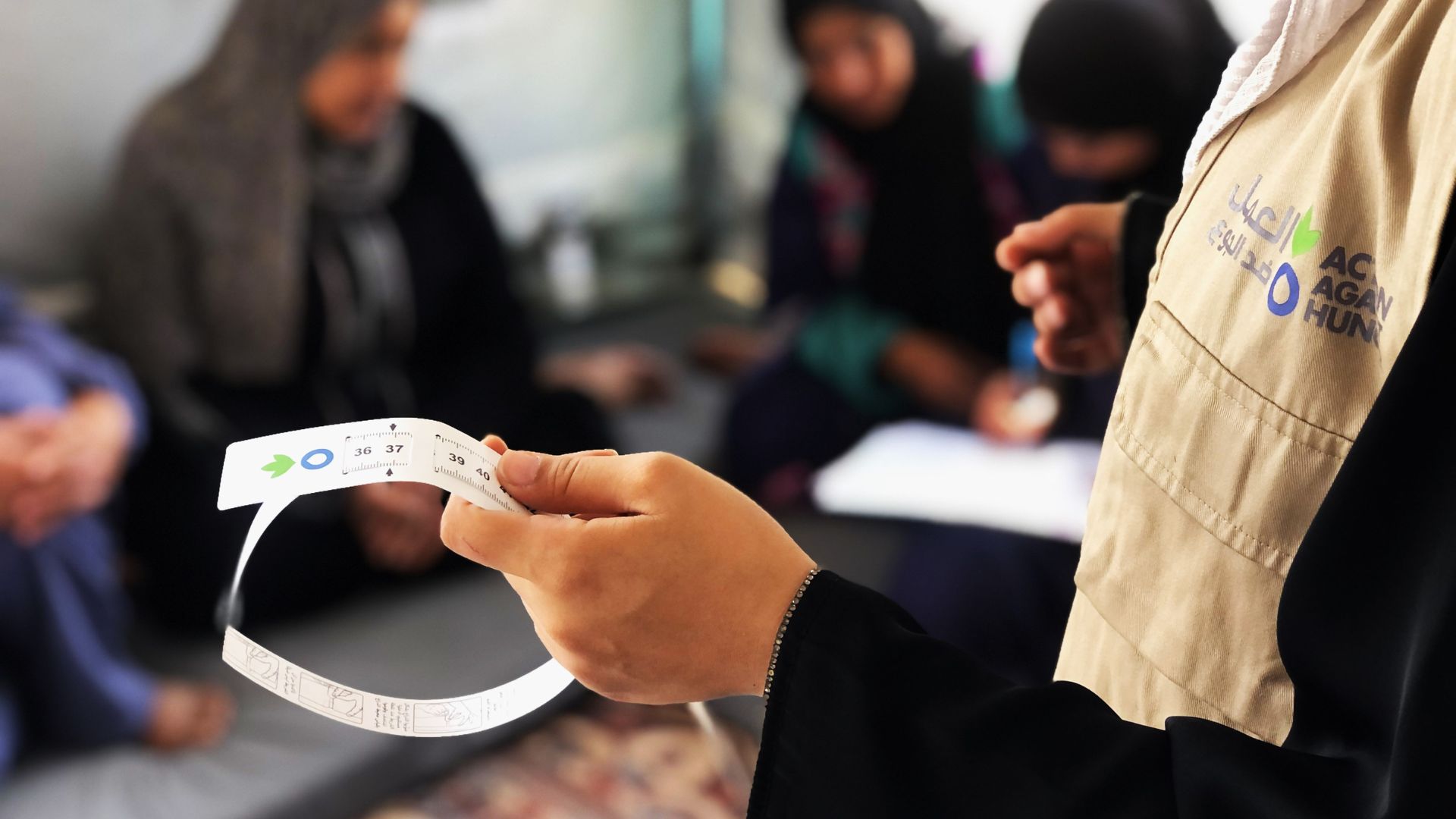 Action Against Hunger team member holding MUAC malnutrition band.