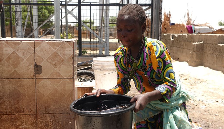 Young adult collecting clean water in Nigeria.